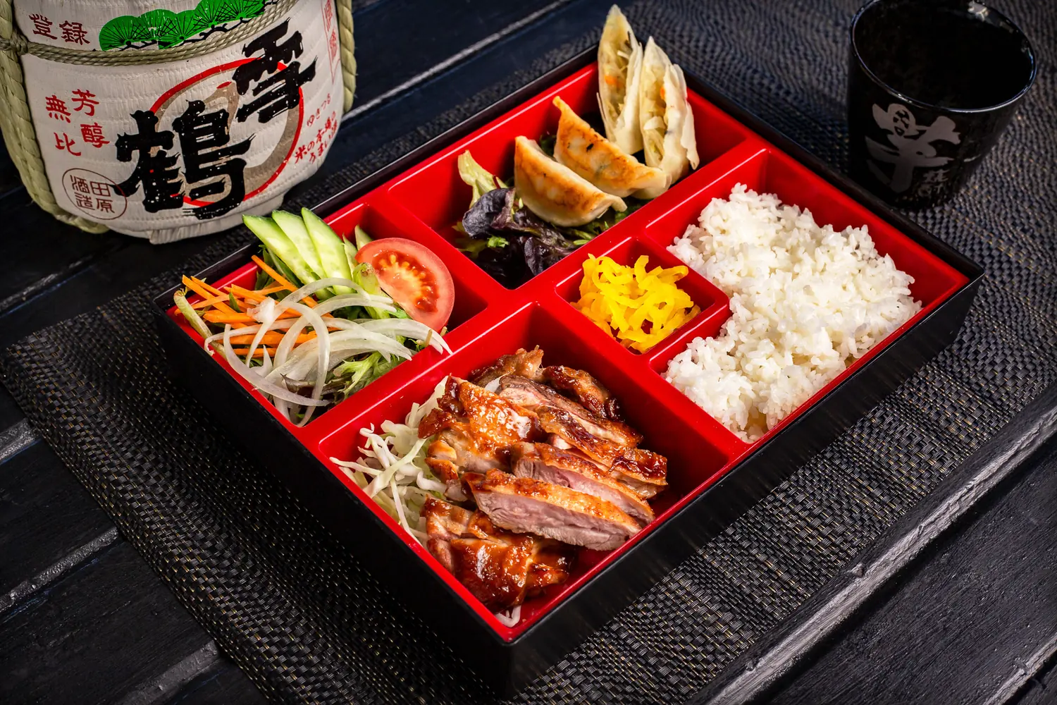 Japanese lunch bento with grilled meat, rice, gyoza, and salad