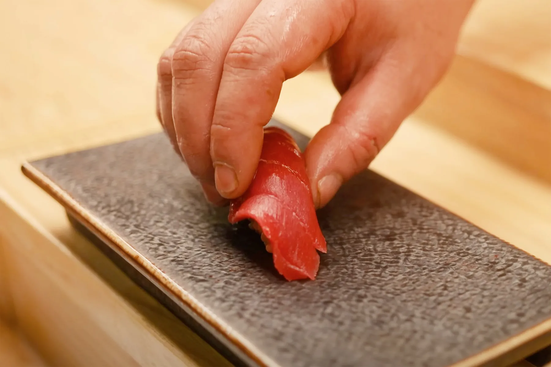 Sushi chef shaping fresh tuna nigiri by hand